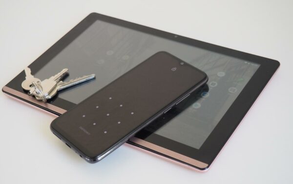 tablet and phone on table, house keys on tablet screen