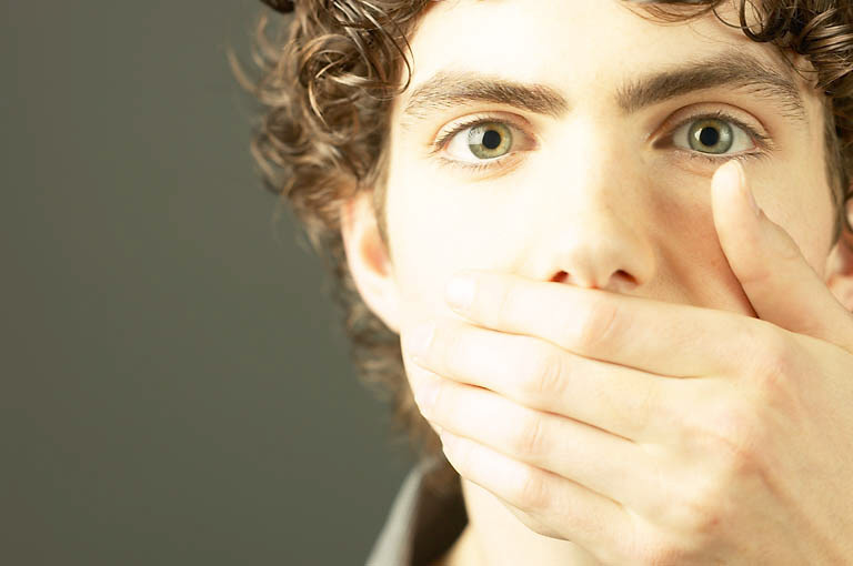 young man surprised, hand covers his mouth